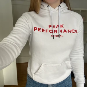 Peak performance hoodie - Jättsnygg vit peak performance hoodie med luva röd text. Bra skick, använd några enstaka gånger. Säljer då hoodien sitter lite tight på mig (föredrar lite mer baggy stil). Hoodien är storlek S men passar på XS-M beroende på hur man vill att den ska sitta. Jag är storlek M. Spegeln är lite smutsig, men hoodien är helt fläckfri☺️ Org. pris: ca 1000kr (minns inte exakt). Säljer för 300 kr + frakt. 