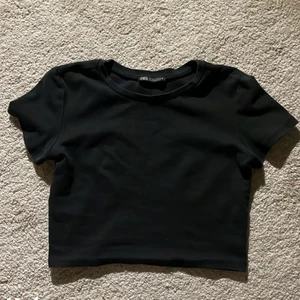 Topp - Snygg topp från Zara i st XS/S, den är stretchig men sitter tight och den är även cropped. Den är i bra skick utan hål och fläckar, säljer för att den inte kommer till användning längre. Färgen är en väldigt mörk grå/svart färg, fint till sommaren!🖤