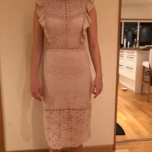 Rosemund spetsklänning, puderrosa - Figurnära klänning som aldrig har använts, fin passform och vackert sydd spets. Prislappen är kvar, originalpris 1598kr.