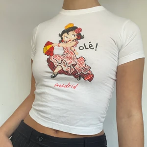 Babytee - Söt babytee med Betty boop! Trycket är slitet vilket syns på sista bilden men annars gott skick. Plagget visas på storlek s men uppskattas passa bättre på en storlek xs! Originellt barnstorlek. Köpare står för 26kr frakt. 
