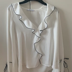 Tunn blus med volanger  - Storlek XS (ganska stor i storleken) Väldigt fin o skön, tunn. Volanger längs bröstet samt knyte längs ner på armen. Lite urringad. Kortare fram till än bak. Frakt ingår ej i priset, betalning genom swish