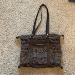 Brun väska - Så fin mönstrad väska i bra skick!! Köpt second hand men vet ej märket<3 perfekt som skolväska då dator och böcker för plats!