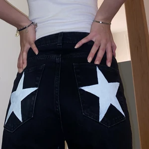 Jeans med stjärnor  - Svarta jeans i modellen Voyage från weekday som även har vita stjärnor på fickorna. Har sprättat upp sömmen vid fötterna så de blev lite längre, har även klippt en slits (se på sista bilden). Storlek 26/32 passar på mig som är 178 cm och oftast bär strl S. ❤️‍🔥❤️‍🔥
