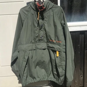 Retro grön parkas L/XL - Jacka i SUPERFINT skick med ficka på magen, luva som går att rulla in i kragen och dragsko längst ner. Fantastiskt fint begagnat kick. Litet hål (se bild).   Sitter mycket oversized på mig som är normal dam Medium. Unisex