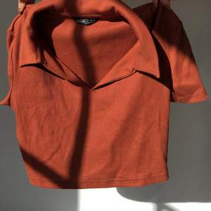 Kroppad tröja i brun/orange med krage. Aldrig använd 