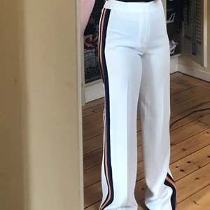 Vit kostymbyxa med ränder  - Vit kostymbyxa från zara med ränder på sidan i svart, blått och gult. Säljer denna för att de var för långa på mig