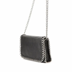 Svart läderväska med silver kedja  - Svart axelremsväska i skinnimitation kantad med silverfärgad kedja. Ett fack med dragkedja på baksidan och ett fack med dragkedja på insidan. Axellänk 105 cm men man kan tvista den för att få den kortare! Oanvänd och därav i perfekt skick💕 Nypris: 500kr