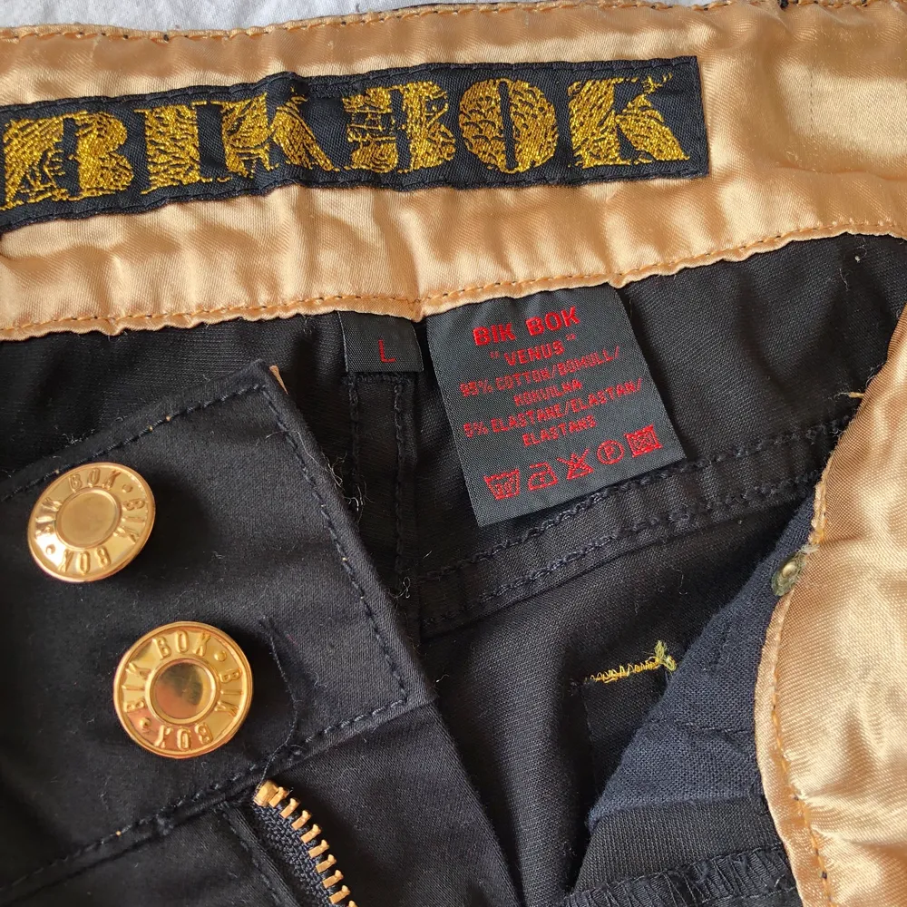 Bik Bok svarta Venus byxor med snygga gulddetaljer. Byxan är normalläng och lite utställda, men ej mkt. Använd fåtal ggr, nyskick. . Jeans & Byxor.