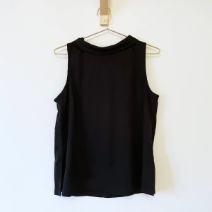 Linne med krage  - Svart linne i satin med krage och dragkedja i nacken. Uppskattningsvis en strl S-M