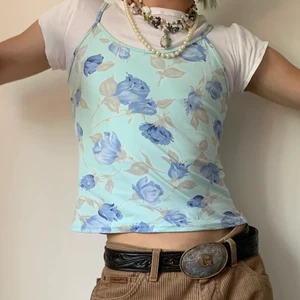 Vintage turkos blommigt blommigt linne  - Vintage turkost superstretchigt linne med grå/bruna och blåa rosor och spagetti straps 🐚 Detta linnet är så fint att ha över en basic ribbad baby tee och ett par jeans som matchar det blåa i rosorna (det bästa är att det finns flera nyanser!) eller ett par bruna byxor, pärlor och funky bälte för att få en mer down to earth outfit! Linnet är också perfekt för att ha till en chill outfit hemma, ett par gråa mjukisbyxor och en zip hoodie så har du en skön och snygg look!