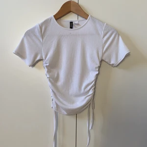 Vit tröja med knyte - Säljer denna tröja med knyte på båda sidorna i strl XS från hm, den kommer tyvärr inte till användning och andvänd ett fåtal ggr.