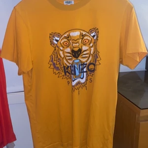 Kenzo Paris t-shirt storlek S - En kenzo Paris t-shirt i orange färg med fler färgad tiger på. Skicket på tröjan är 9-10 av 10 och är köpt på johnells. OBS KÖPAREN STÅR FÖR FRAKT 