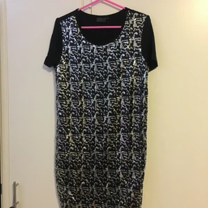 Klänning  - Oanvänd klänning med silvriga och svarta paljetter på svart tyg. Storlek 36/38, stor i storleken. 