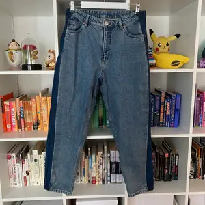 Blå jeans med mörklblå ränder på sidorna från Monki. Inuti står det att dom är av modellen TAIKI HIGH WAIST BALOON LEG (storlek 31). Dom är i 100% bomull och är 7/8 längd. Använda men i bra skick.