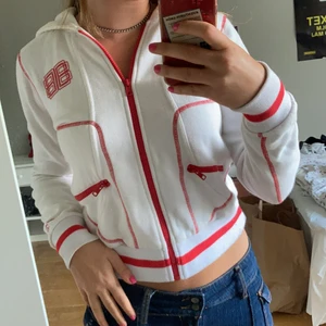 Vit zip up med röda detaljer - Superskön vit zip up med röda detaljer från Björn Borg!