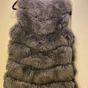 Grå-brun pälsväst (ej äkta) - Jättefin väst perfekt för våren.  Ett par knappar trasiga men går lätt att byta ut. 