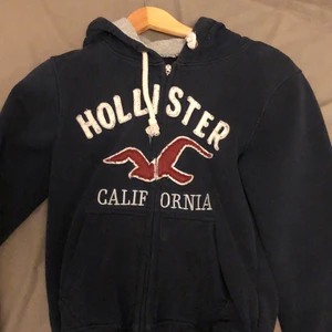 Hollister - Säljer denna mörkblå Hollister California tjocktröjan. Väldigt bra skick bara 2 små fläckar som inte syns när man har på sig den. Köpt från Hollister butiken i Stockholm. Lite slitet vid handleden men annars bra. Behöver bli av med lite kläder 😊  köparen står för frakten