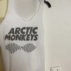 Vitt linne med ”Arctic Monkeys” tryck. Strl S. Lös passform.
