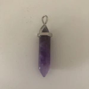 Kristall smycke - Kristall hänge av äkta ametist! Den är ungefär 2,5 cm lång. Köparen står för frakten. Köpte den för 90kr på en kristall affär.Kontakta via intresse eller frågor.