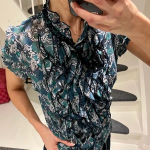 Saint Tropez blus - Klassiska blusen från Saint Tropez med härligt krås. Sitter så fint på! Underbar t mönster i grönt och blått! Stlk S. Använd ett fåtal tillfällen!