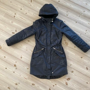 Vaxad jacka från Elvine - Varm jacka med luva, perfekt för regniga höstdagar. I en snygg blå färg. Nypris 2300 kr