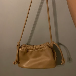 Väska - En väska i jättebra skick från Nelly, beige, liten och går att justera längden:)  Köpte den för 399kr