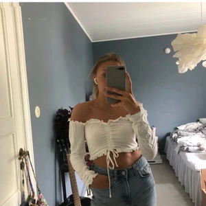 Vit topp med volang - Superfin topp från Nelly med volang och drawstring! Storlek xs och går både att använda som off shoulder eller inte. Knappt använd, fint skick!💘
