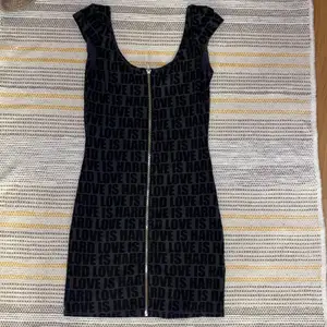 Kort svart/mörkgrå klänning med dragkedja framtill och text. Minns ej vart jag köpt denna men aldrig använt.