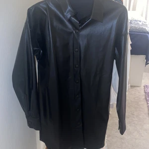 Skinnjacka - En svart skinnjacka som når ner en bit ner till låren. Väldigt snygg och tunn. 