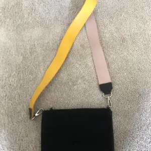 Snygg enkel svart väska med löstagbart gult eller rosa band till. 