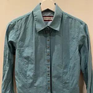 Blå skjorta i fint skick från The Shirt Factory i storlek 36 med tryckknappar.