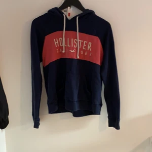 Hoodie från hollister  - Mörkblå hoodie med  rosa rand med text i. En skön hoodie lite tunnare än vad de brukar vara passar till sommarkvällar. Använd rätt mycket men inga skador eller trådar som är uppe. Den har en stor ficka i mitten.