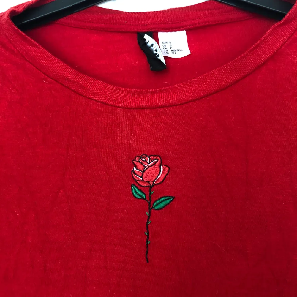 En röd t-shirt med en ros på, storlek S. Skönt material och fin färg!❣️ Kan mötas i Kalmar eller skicka, köparen betalar frakt ✨. T-shirts.