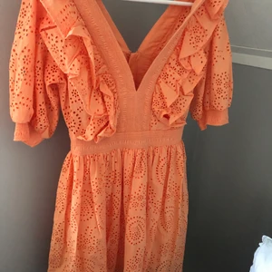 Broderad volangklänning orange - Orange sommarklänning med V ringning både bak och fram. Passar perfekt till midsommar! Slutsåld! Aldrig använd