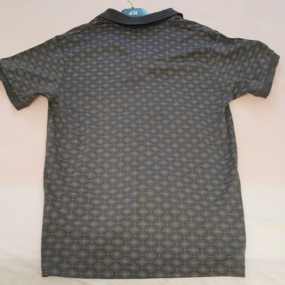 En grå Polo( Ralph Lauren) T-shirt med oranga prickar. Köptes för 2 år men har inte används sedan de första 3 månaderna efter köpet. T-shirten är k storleken L. . T-shirts.
