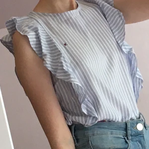 Tommy hilfiger blus - Jättesöt vit och blå randig Tommy Hilfiger blus men broderade blommor, som knappt är använd. Köptes för några  år sedan men har inte använt den så mycket därför säljer jag den. Kan mötas upp eller frakta men då står köparen för frakten.