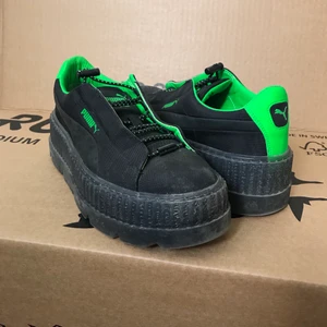 Puma Fenty Creepers - Säljer dessa plattformssneakers från Puma och deras samarbete med Rihannas Puma Fenty. De är i storlek 40, är svarta med gröna detaljer och har en dragsko istället för vanlig snörning. Själva skon är ganska smal i modellen men är annars väldigt bekväm.  Skorna har använts ett fåtal gånger och är därför i väldigt fint skick. Är lite sandiga på bilden, men de torkas av innan försäljning. Säljs utan låda.   Köptes några år tillbaka för dryga 1 000kr. Om ni är intresserade, skicka iväg ett meddelande med det pris ni tycker skorna är värda! 