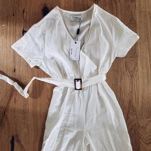 Byxdress i linne från NA-KD - Säljer en vit byxdress i linne från Hannalicious x NA-KD. Helt oanvänd med prislappen kvar. 200kr plus frakt