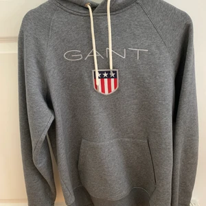 Grå GANT hoodie - Grå GANT hoodie i storlek M. Fick den i julklapp och har aldrig använt den. Nypris för denna är 1099kr, men jag säljer den för 400kr. 