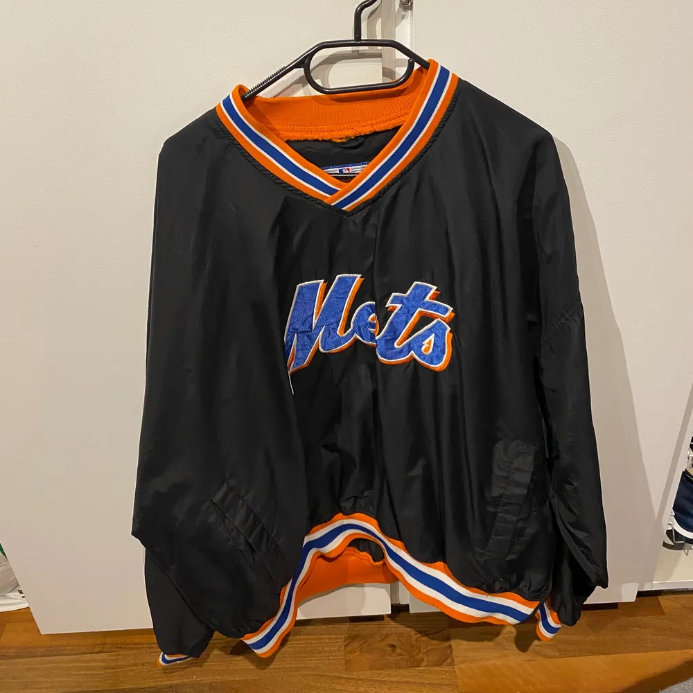 Tunn, svart skaljacka med baseball-laget Mets på. Köpt secondhand men använd endast en gång av mig. Den är i fint skick. Dragkedja längst ner och fickor. Finns ingen storlek på men där är väldigt baggie och tuff (skulle gissa på XL). 200kr+ frakt. Fråga för fler bilder🤩🤩. Jackor.