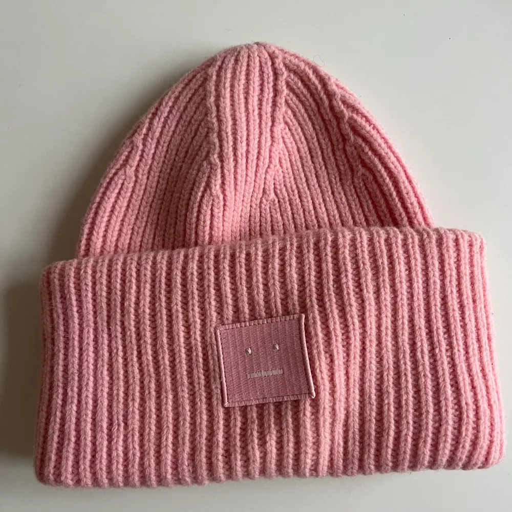 Face logo beanie från Acne i färgen Blush Pink. Köpt för 1300kr på Acne i Stockholm. Toppskick utanpå. Tyvärr en liten sminkfläck på insidan av mössan vid pannan 🙃 Se bild. Inget som syns när man har på sig mössan och går säkert att tvätta bort. Glöm inte att bud är bindande💛. Accessoarer.