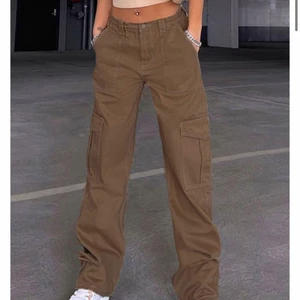 Bruna Cargobyxor - Det är ett par bruna cargobyxor, inte samma märke som första bilden men samma passform. De är thriftade så vet inte faktsikt märke men i gott skick och är i storlek M. 