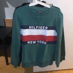 Tommy Hilfiger tröja - strl 164 - hej! jag säljer min nu gammla gröna Tommy Hilfiger sweatshirt. har växt ur den och inte använt så mycket. det är storlek som passarn barn runt 164cm lång. vid frågor eller funderingar skicka gärna ett medelande :) kolla in min profil för har liknande kläder där, kan komma på något rabatt-packet för alla kläder också!