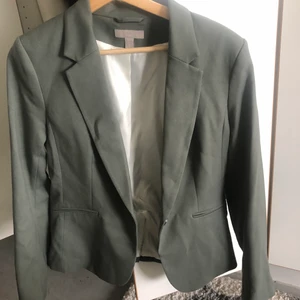 Grön/grå kavaj storlek 40 - En helt ny kavaj från H&M, använd en gång. Storlek 40 men sitter perfekt på mig som brukar ha 36 och inte vill att den ska sitta så tajt.