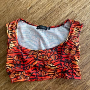 Top från Prettylittlething - Söt topp i varma färger med fjärilar på från PLT. Storlek 34.
