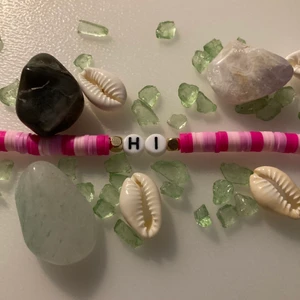 Rosa armband  - Rosa armband runt 20cm. Med en liten text (HI).