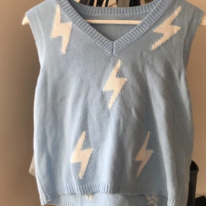 Väst  - Ljusblå stickad väst med vita blixtar på. Oanvänd. Storlek M, men passar även som S/XS. Köparen står för frakten.