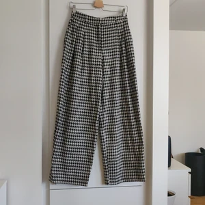 Kostymbyxor H&M stl 36 - Coola kostymbyxor i vintage stil. Rutiga men i den gamla stilen. Svarta och vita/beiga rutmönster. Passformen är att den sitter åt över höft/midjan sedan ett rakt fall med Vida ben. Storlek 36. Fraktkostnaden tillkommer.