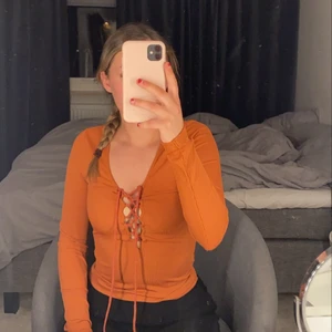 Topp - En orange topp med knyt vid bröstet. Jättefin och skön. Materialet är ribbat 