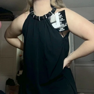 Svart klänning!!! - Supersnygg svart klänning med smyckad rigning runt halsen! Köptes för 500kr, säljer för 120kr! Säljes pga inte längre kommer till användning💞